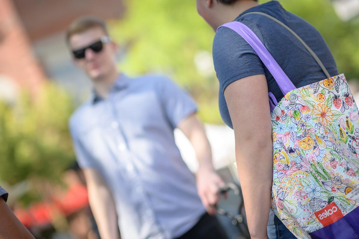 一名学生在校园里带着一个可重复使用的袋子