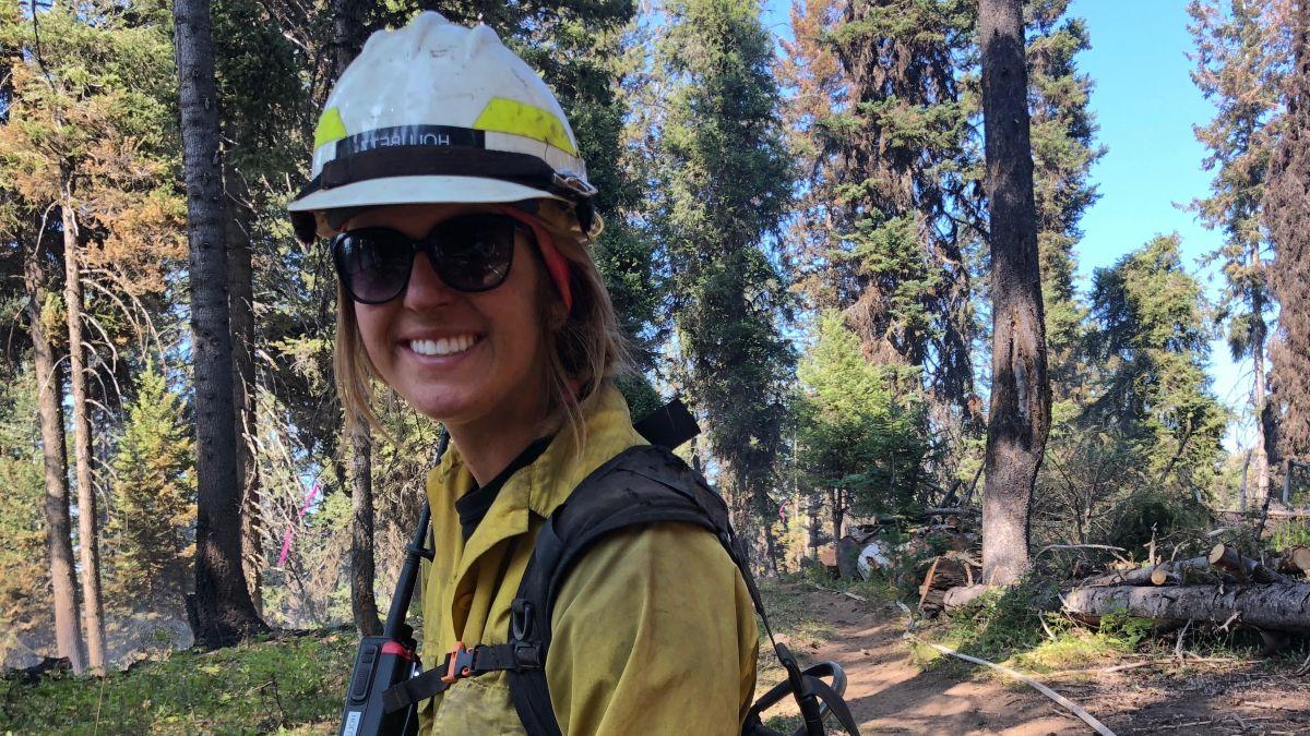 Heidi Holubetz穿着黄绿相间的消防装备站在森林里.