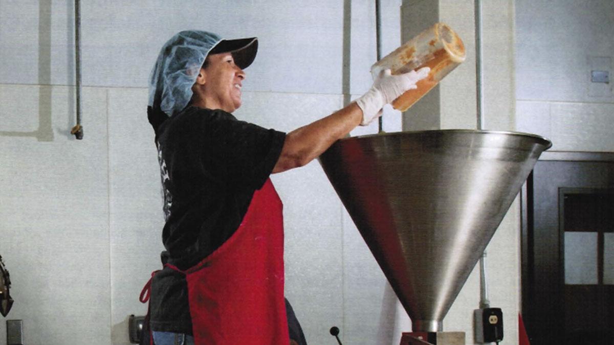 Woman putting hummus into filler machine hopper