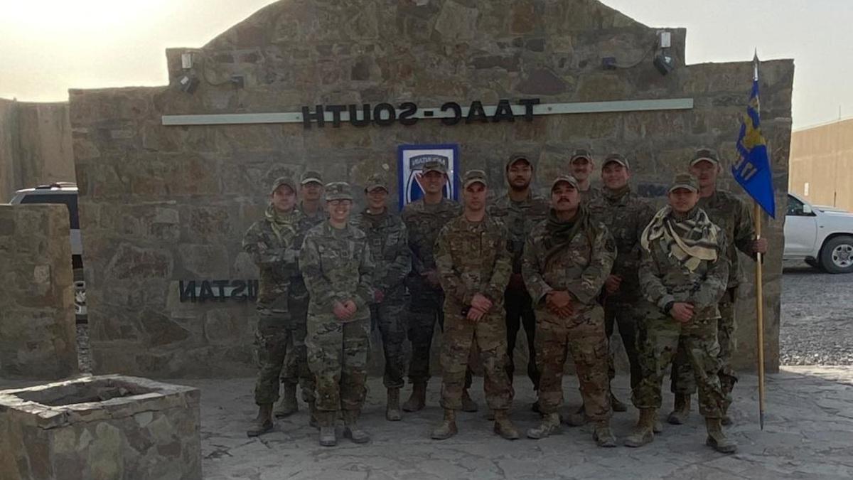 尤金·罗素(Eugene Russell)和其他11名身穿军装的队员站在TAAC South的标志性标志前.